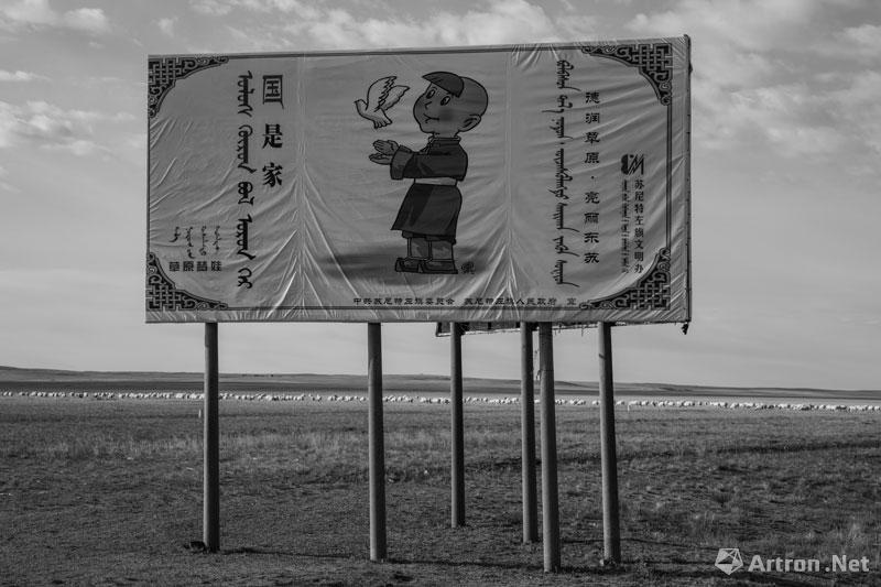 董斯洋作品：2015年9月27日，锡林郭勒盟苏尼特左旗，穿着新衣的广告牌似乎对蓝天白云、草地与羊群诉说着他的梦。